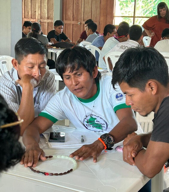 Three indigenous Peruvian community health workers seated around a training table in the Amazon.